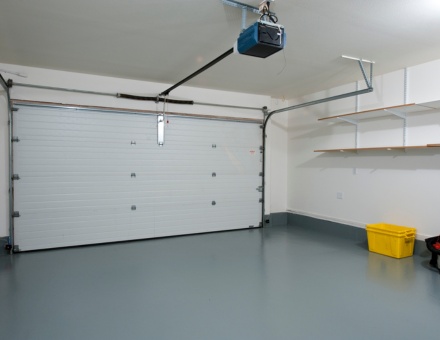 Spacious garage interior with clean floors and organized shelving in a residential setting Belt drive garage door opener installation and repair